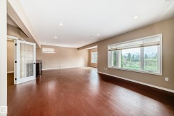 Expansive room featuring wood-finish flooring, recessed lighting, and a large picture window with outdoor scenery - 