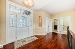 Entryway featuring a decorative transom and sidelight windows, wood-finish flooring, a ceiling-mounted light fixture, an arched wall niche, and white interior doors - 
