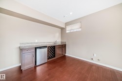 Wet bar featuring wood-finish flooring, recessed lighting, and a window with a roller shade - 