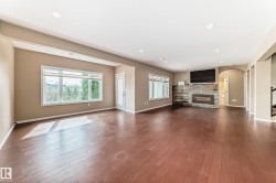 Spacious interior featuring wood-finish flooring, recessed lighting, and a stone-clad fireplace with built-in shelving - 