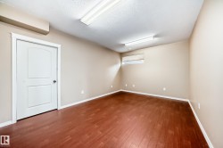 Room featuring wood-finish flooring, neutral wall paint, and a white ceiling with textured finish - 