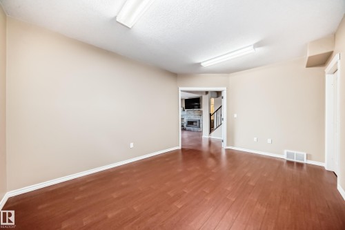 Spacious room featuring wood-finish flooring, light beige wall paint, white trim, and two overhead fluorescent light fixtures - 527 Callaghan Point(E), Edmonton, AB - Indoor Photo Showing Other Room