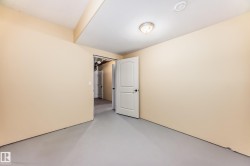 Finished basement space with light beige walls and a grey painted concrete floor - 
