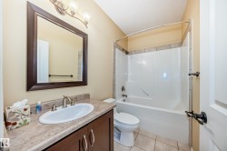 Full bathroom featuring a dark wood-finish vanity with a cultured marble countertop, an undermount sink with a brushed nickel faucet, and a large framed mirror - 
