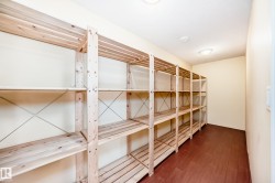 Dedicated storage room featuring extensive wood shelving, durable wood-finish flooring, and ceiling-mounted lighting - 