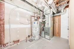 Utility room featuring a water heater, furnace, exposed ductwork, PEX plumbing, and a concrete floor - 