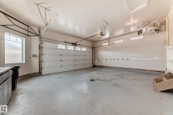 Two-car garage featuring a painted concrete floor, overhead garage door with transom windows, and built-in shelving - 