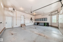 Spacious garage featuring concrete flooring, built-in cabinetry, overhead lighting, and two exterior doors - 