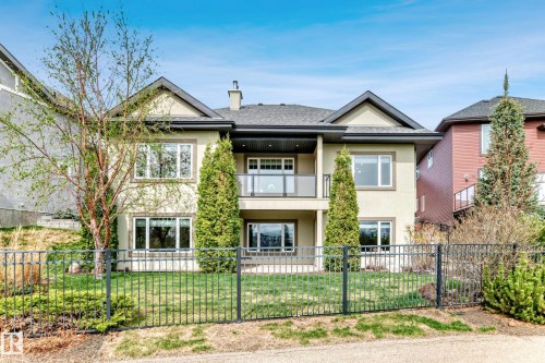 Stucco exterior with multiple windows, a second-story balcony with glass railing, and a fenced yard - 527 Callaghan Point(E), Edmonton, AB - Outdoor With Facade