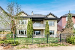 Stucco exterior with multiple windows, a second-story balcony with glass railing, and a fenced yard - 