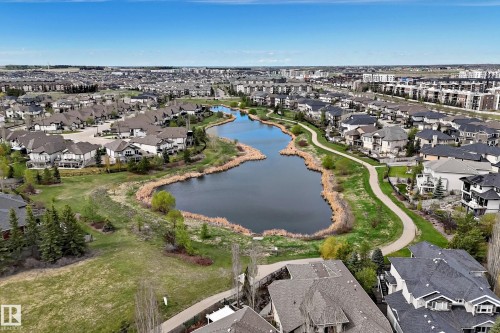 Expansive neighborhood featuring a large central pond, surrounding green spaces, paved pathways, and a collection of residential properties with varied architectural styles - 527 Callaghan Point(E), Edmonton, AB - Outdoor With View