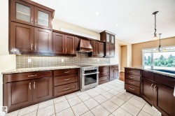 Modern kitchen featuring dark wood-finish cabinetry, granite countertops, and a full-height tiled backsplash - 