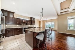 Kitchen featuring dark wood cabinetry, stainless steel appliances, and a mosaic tile backsplash - 