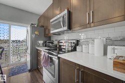 Modern kitchen featuring wood-finish cabinetry, stainless steel appliances, white subway tile backsplash with glass accent, and light-toned countertops - 