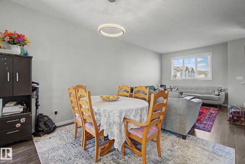Open-concept living space featuring wood-finish flooring, a modern chandelier, and ample natural light from a large window - 17 320 Secord Boulevard, Edmonton, AB - Indoor