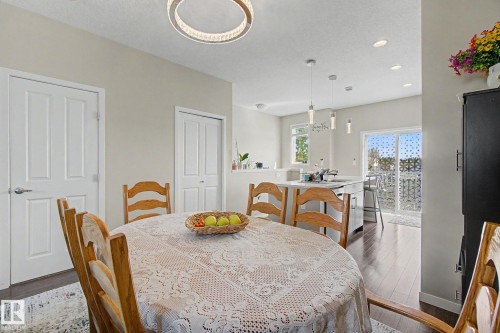 Dining area featuring a contemporary circular chandelier and wood-finish flooring - 17 320 Secord Boulevard, Edmonton, AB - Indoor Photo Showing Dining Room