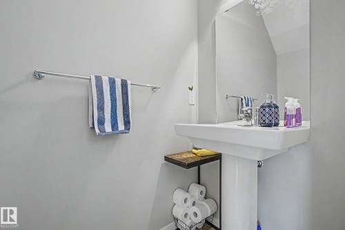 Pedestal sink with chrome faucet, large wall-mounted mirror, and a towel bar - 17 320 Secord Boulevard, Edmonton, AB - Indoor