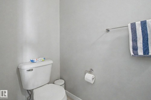 White toilet with a wall-mounted toilet paper holder - 17 320 Secord Boulevard, Edmonton, AB - Indoor Photo Showing Bathroom