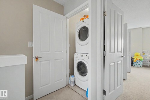 Dedicated laundry closet featuring a stacked washer and dryer unit - 17 320 Secord Boulevard, Edmonton, AB - Indoor Photo Showing Laundry Room