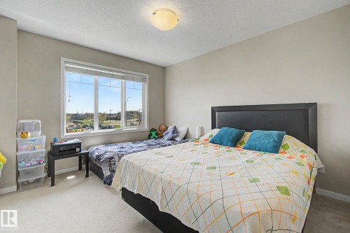Bright bedroom featuring light-toned walls and plush carpet flooring - 17 320 Secord Boulevard, Edmonton, AB - Indoor Photo Showing Bedroom