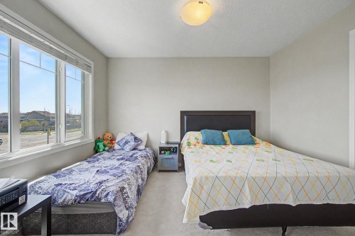 Bright room featuring a large window, neutral wall paint, and light-colored carpeting - 17 320 Secord Boulevard, Edmonton, AB - Indoor Photo Showing Bedroom