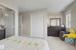 Bedroom featuring neutral-toned walls, light-colored carpeting, a window with natural light, and a bi-fold closet - 