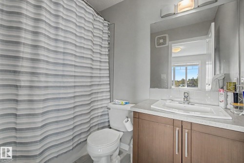 Bathroom vanity featuring wood-finish cabinetry, a rectangular undermount sink, and a laminate countertop - 17 320 Secord Boulevard, Edmonton, AB - Indoor Photo Showing Bathroom