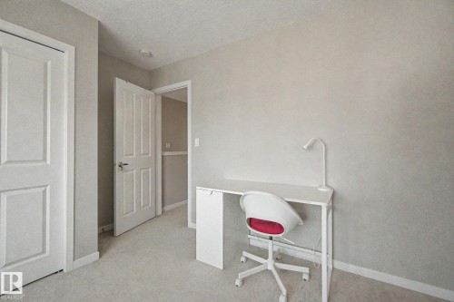 Carpeted room featuring a neutral color palette, white trim, and a white paneled door - 17 320 Secord Boulevard, Edmonton, AB - Indoor