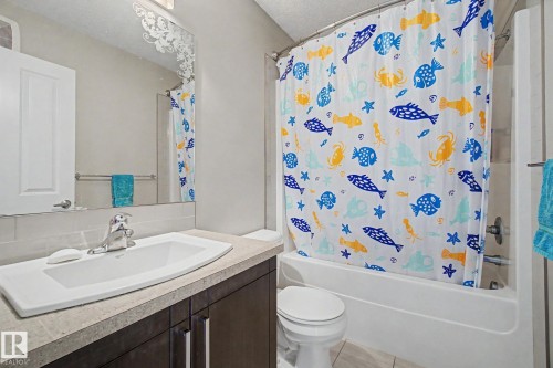 Bathroom featuring a white vanity with a rectangular sink, a chrome faucet, and dark wood-finish cabinetry - 17 320 Secord Boulevard, Edmonton, AB - Indoor Photo Showing Bathroom