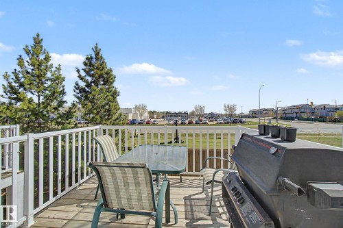 Spacious elevated deck featuring wood-finish flooring and a white railing system - 17 320 Secord Boulevard, Edmonton, AB - Outdoor