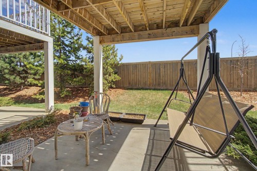 Covered concrete patio with overhead wood-finish decking, supported by white columns - 17 320 Secord Boulevard, Edmonton, AB - Outdoor With Deck Patio Veranda With Exterior