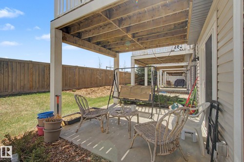 Covered concrete patio area with overhead wood decking and white support columns - 17 320 Secord Boulevard, Edmonton, AB - Outdoor With Exterior