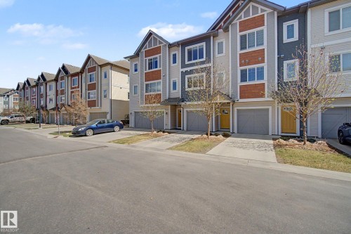 Contemporary townhome exterior featuring multi-toned siding, gabled rooflines, a private driveway, and an attached garage - 17 320 Secord Boulevard, Edmonton, AB - Outdoor With Facade
