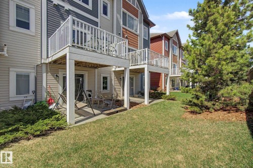 Rear exterior showcasing a private upper-level balcony, a ground-level patio, and a manicured lawn - 17 320 Secord Boulevard, Edmonton, AB - Outdoor