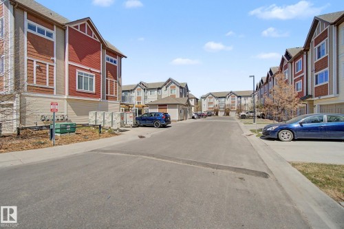 Multi-level residential buildings featuring red and beige siding, gabled rooflines, and multiple windows - 17 320 Secord Boulevard, Edmonton, AB - Outdoor With Facade