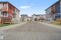 Tree-lined street featuring multi-level townhomes with diverse exterior finishes - 
