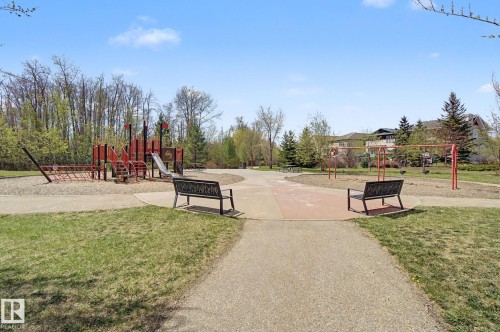Community park featuring a play structure with slides and climbing elements, a swing set, and integrated park benches - 17 320 Secord Boulevard, Edmonton, AB - Outdoor