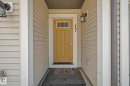 Welcoming entry featuring a bright yellow door with upper glass panes, flanked by two outdoor wall sconces - 17 320 Secord Boulevard, Edmonton, AB  - Outdoor With Exterior 