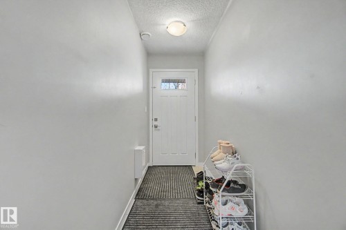 Entryway featuring a white door with transom-style window, overhead flush-mount lighting, and light grey painted walls - 17 320 Secord Boulevard, Edmonton, AB - Indoor Photo Showing Other Room
