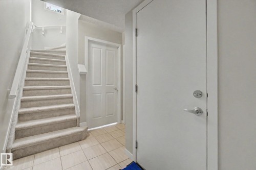 Staircase with light-colored carpeted treads, white handrails, and balusters - 17 320 Secord Boulevard, Edmonton, AB - Indoor Photo Showing Other Room