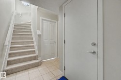Staircase with light-colored carpeted treads, white handrails, and balusters - 