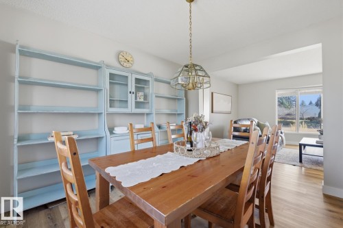 Dining area featuring light wood-finish flooring, a built-in shelving unit, and an overhead glass-paneled chandelier - 17604 85 Avenue, Edmonton, AB - Indoor Photo Showing Dining Room