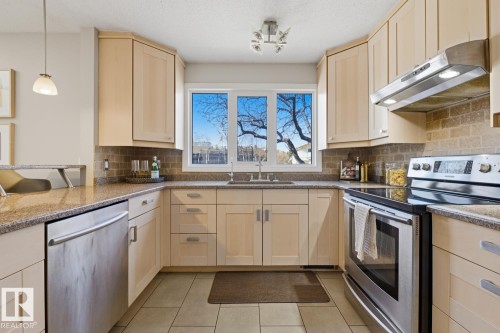 U-shaped kitchen featuring wood-finish cabinetry, granite countertops, and a subway tile backsplash - 17604 85 Avenue, Edmonton, AB - Indoor Photo Showing Kitchen