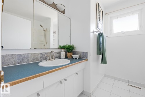 Bathroom featuring a vanity with a blue countertop, a built-in sink, and a two-door mirror cabinet - 17604 85 Avenue, Edmonton, AB - Indoor Photo Showing Bathroom