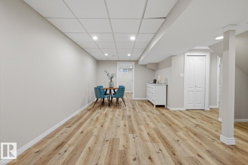 Spacious finished area featuring wood-finish flooring, recessed lighting, drop ceiling, and crisp white trimwork - 17604 85 Avenue, Edmonton, AB - Indoor Photo Showing Other Room