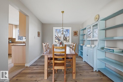 Dining area featuring wood-finish flooring, a contemporary pendant light fixture, and a built-in cabinetry unit with open shelving and glass-front doors - 17604 85 Avenue, Edmonton, AB - Indoor
