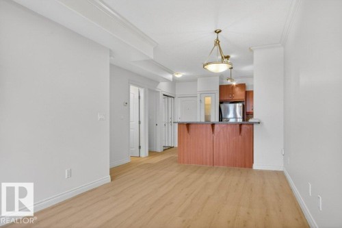 Open-concept living area featuring wood-finish flooring, white baseboards, and crown molding - 223 10121 80 Avenue, Edmonton, AB - Indoor Photo Showing Kitchen