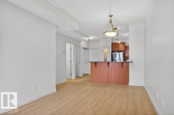 Open-concept living area featuring wood-finish flooring, white baseboards, and crown molding - 