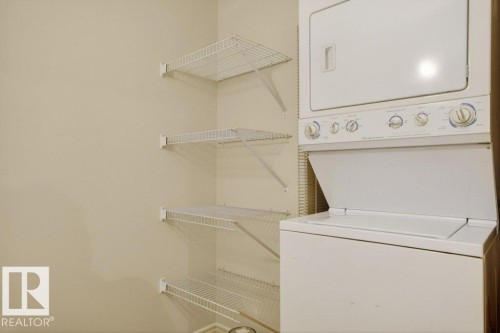 Laundry room featuring a stacked washer and dryer unit and multiple wire shelving units. - 223 10121 80 Avenue, Edmonton, AB - Indoor Photo Showing Laundry Room