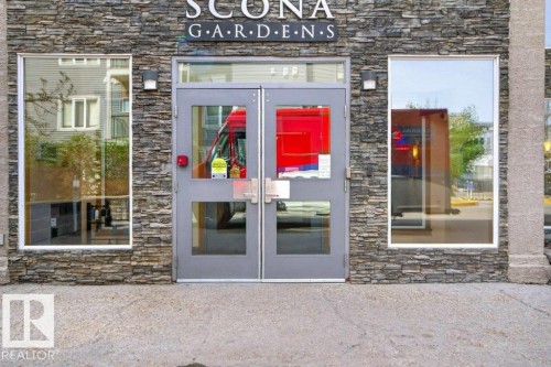 Main entrance featuring stacked stone facade, double glass-paneled doors, and two large windows. - 223 10121 80 Avenue, Edmonton, AB - Outdoor